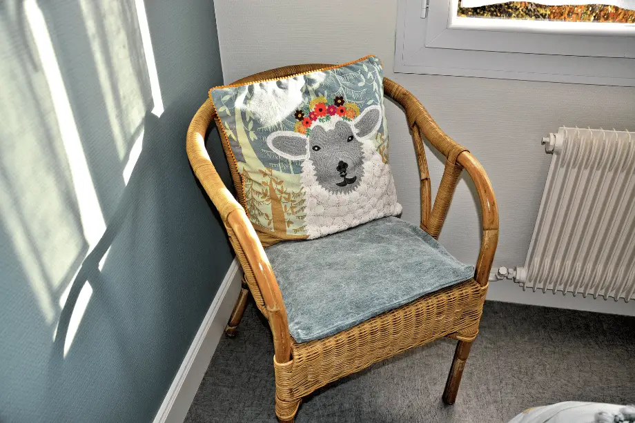 Fauteuil en osier avec coussin décoratif dans la suite Boitfort